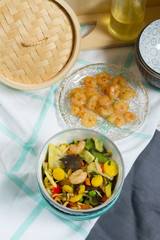 Asian food with vegetables and shrimps. Sesame oil, bowls, bamboo steamer.