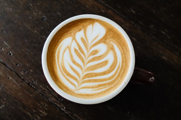 Coffee cup with latte art on the wood table