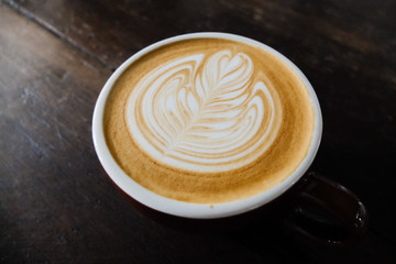 Coffee cup with latte art on the wood table