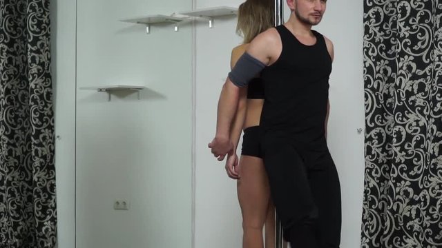 Man and woman holding hands and standing back to back sitting down on the floor