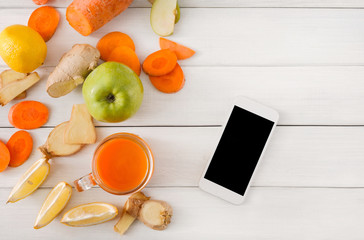Detox carrot smoothie ingredients, top view on white with mobile screen