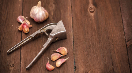 masher for garlic and garlic on a wooden background