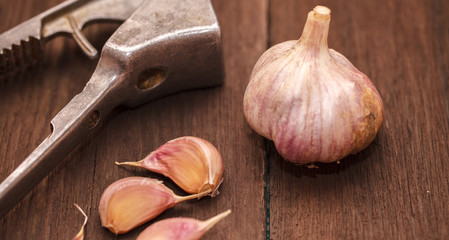 masher for garlic and garlic on a wooden background