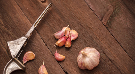 masher for garlic and garlic on a wooden background