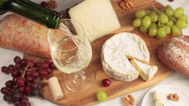 White wine poured into glass, with cheese and bread