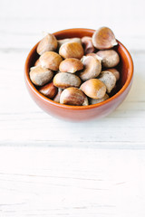 Raw chestnuts in ceramic bowl.