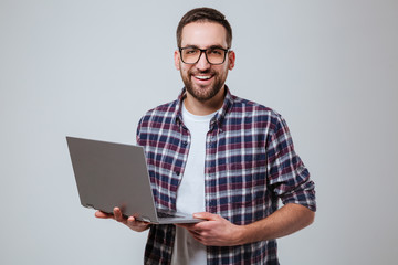 Smiling Bearded man in eyeglases holding laptop