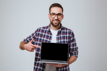 Bearded man in eyeglases showing blank laptop screen