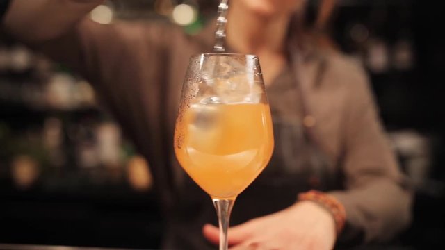 barmaid with glass and stirrer preparing cocktail