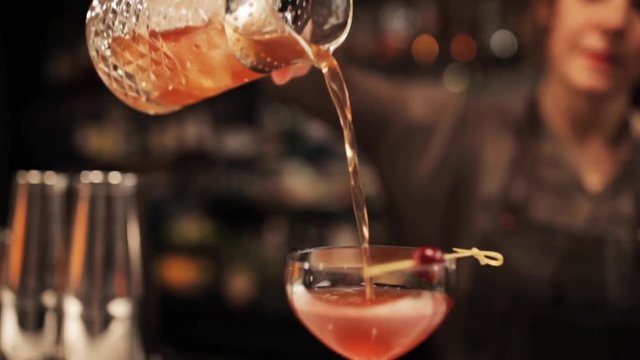 barmaid with glass and jug preparing cocktail