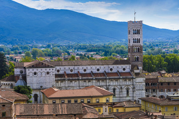 Fototapeta na wymiar Side ship and bell tower of the Duomo di San Martino in Lucca in the background the mountains_Lucca, Tuscany, Italy