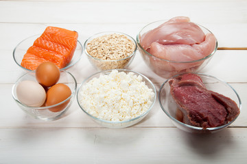 Proteins, fish, cheese, eggs, meat and chicken on a white wooden background