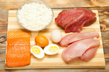 Protein diet, fish, cheese, eggs, meat and chicken on a wooden background