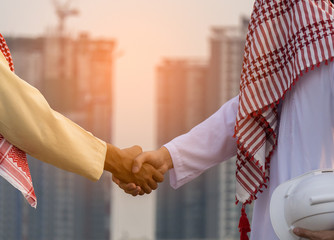 Successful Arabic business people shaking hands on cityscape background