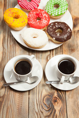 Two cups with coffee and donuts on a wooden background