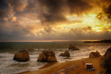 Sunset in the ocean with clouds on the beach Praia da Rocha with rock formations. Portimao, Algarve, Portugal.