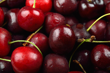 Pile of red cherries with drops of water on them, just removed from the refrigerator. Fresh fruit background texture.