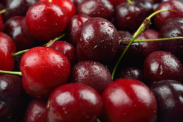Pile of red cherries with drops of water on them, just removed from the refrigerator. Fresh fruit background texture.