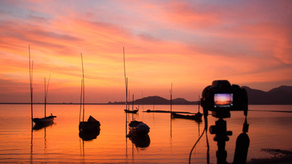 Fototapeta premium Camera standing on tripod at sunset at the sea in Thailand; landscape