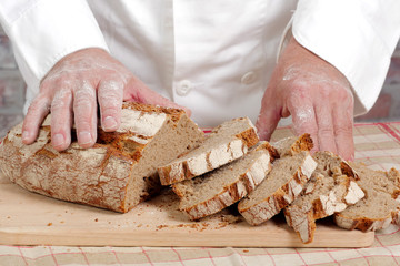 Baker hands with fresh bread on wood table