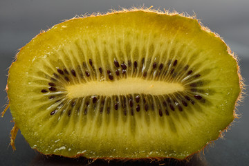 Close up of half kiwi with wizened skin on dark reflection background. Natural organic vegetarian food. Healthy snack