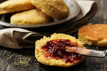 Homemade Cornmeal Biscuits with strawberry jam on wooden background, selective focus