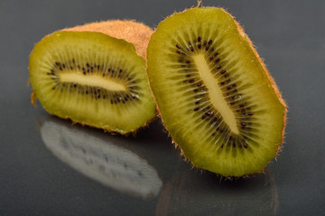 Close up of a kiwi cut in two with wizened skin on dark reflection background. Natural organic vegetarian food. Healthy snack