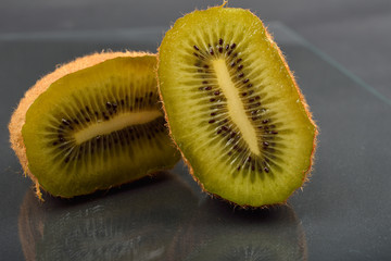 Close up of a kiwi cut in two with wizened skin on dark reflection background. Natural organic vegetarian food. Healthy snack