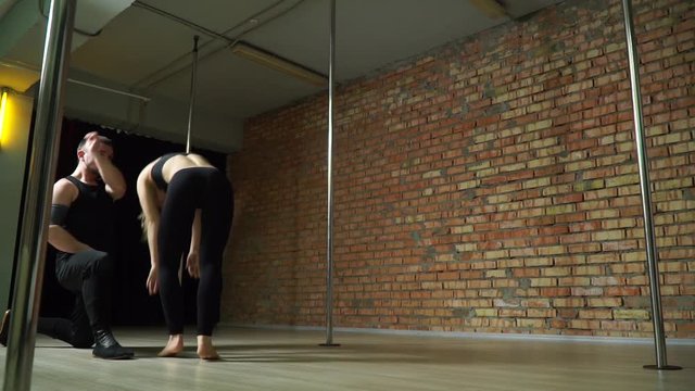 The guy on the training helps the girl to do a coup