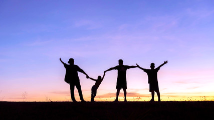 Happy family of four people, mother, father, son and daughter in meadow.