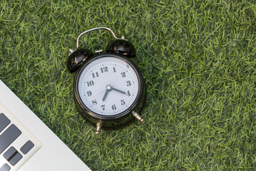 The clock and notebook on the green grass.