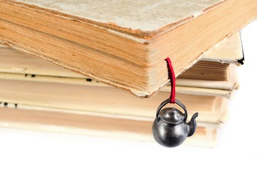 Stack of various used books with an original hand-made bookmark in the form of teapot