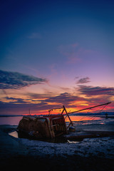 The old fishing boat capsized on sea at sunset in Phuket, Thailand.