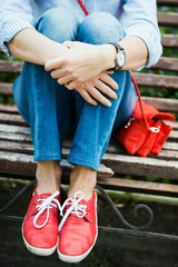 девушка в красных кедах сидит на скамье