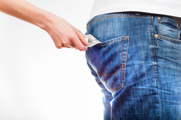 Women's hands pulling the dollar bill out of men's jeans back pocket.