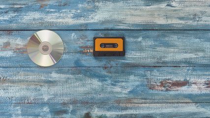  Cd disk and audio tape on an old vintage blue color background . Concept of technology progress