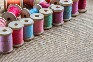 many different colorful thread on wooden background