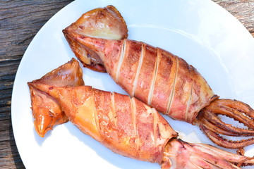 Grilled squid with lemon on white plate on wood table,sea food of Thailand