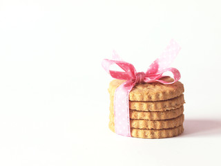 Pile of cookies or biscuits wrapped in pink ribbon with bow on white background