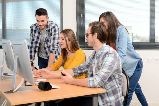group of young cool hipster creative business people in casual wear working together in a meeting room of startup company looking at photography on computer