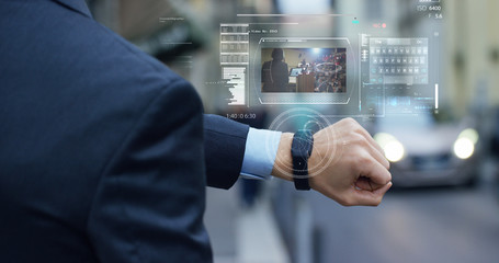 A businessman is followed by a conference on the economy and finance that appears in hologram clock futuristic and technological. Concept: network, conference, technology, augmented reality and future