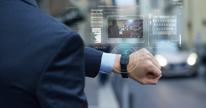 A businessman is followed by a conference on the economy and finance that appears in hologram clock futuristic and technological. Concept: network, conference, technology, augmented reality and future