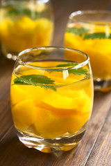 Refreshing peach, lemon balm and white wine punch or wine cooler in glasses, photographed on dark wood with natural light (Selective Focus, Focus on the rim of the glass)