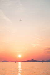 Amazing sunset background with sea, mountains, sky and round sun.