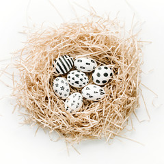 Obraz premium Fancy Easter eggs in nest on white background. Flat lay, top view. Traditional spring concept.