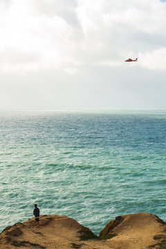 Man Standing On Cliff Top, Aircraft Flying Over Sea 