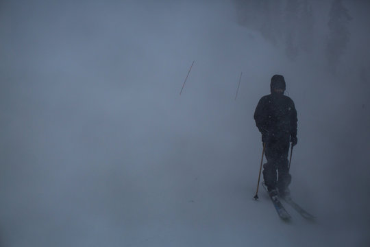 Skier descending snowy slope in blizzard 