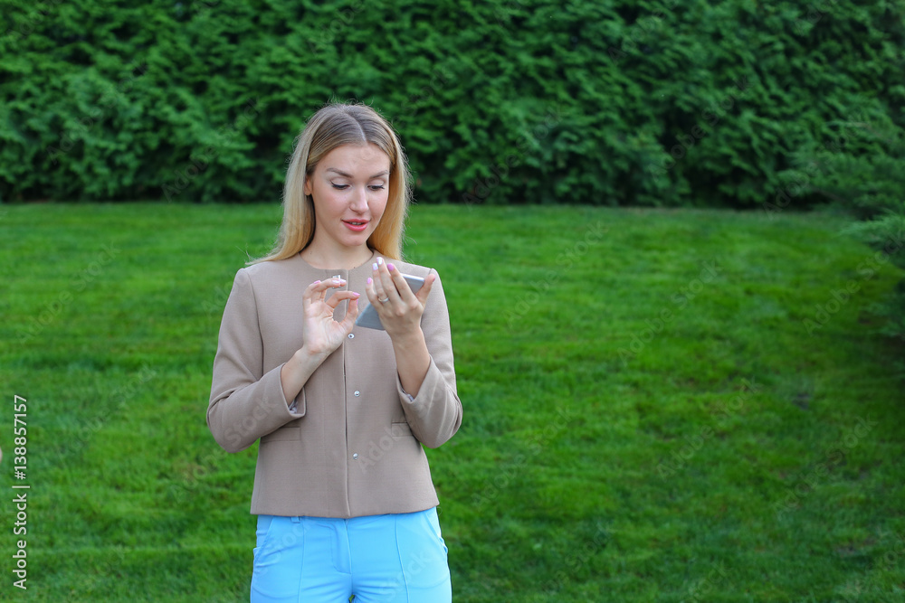 Wall mural Beautiful female looking at smartphone screen and smiles, stands