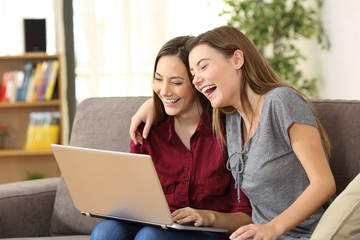 Joyful roommates watching videos in a laptop