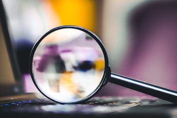 Technology search background. Magnifying glass on computer keyboard with shallow depth of field and...